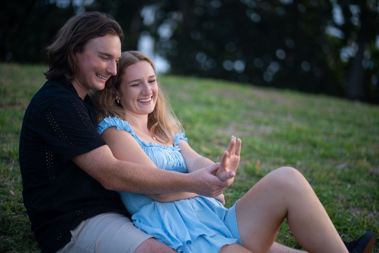 Engagement session in Miami with couple sitting on grass laughing together
