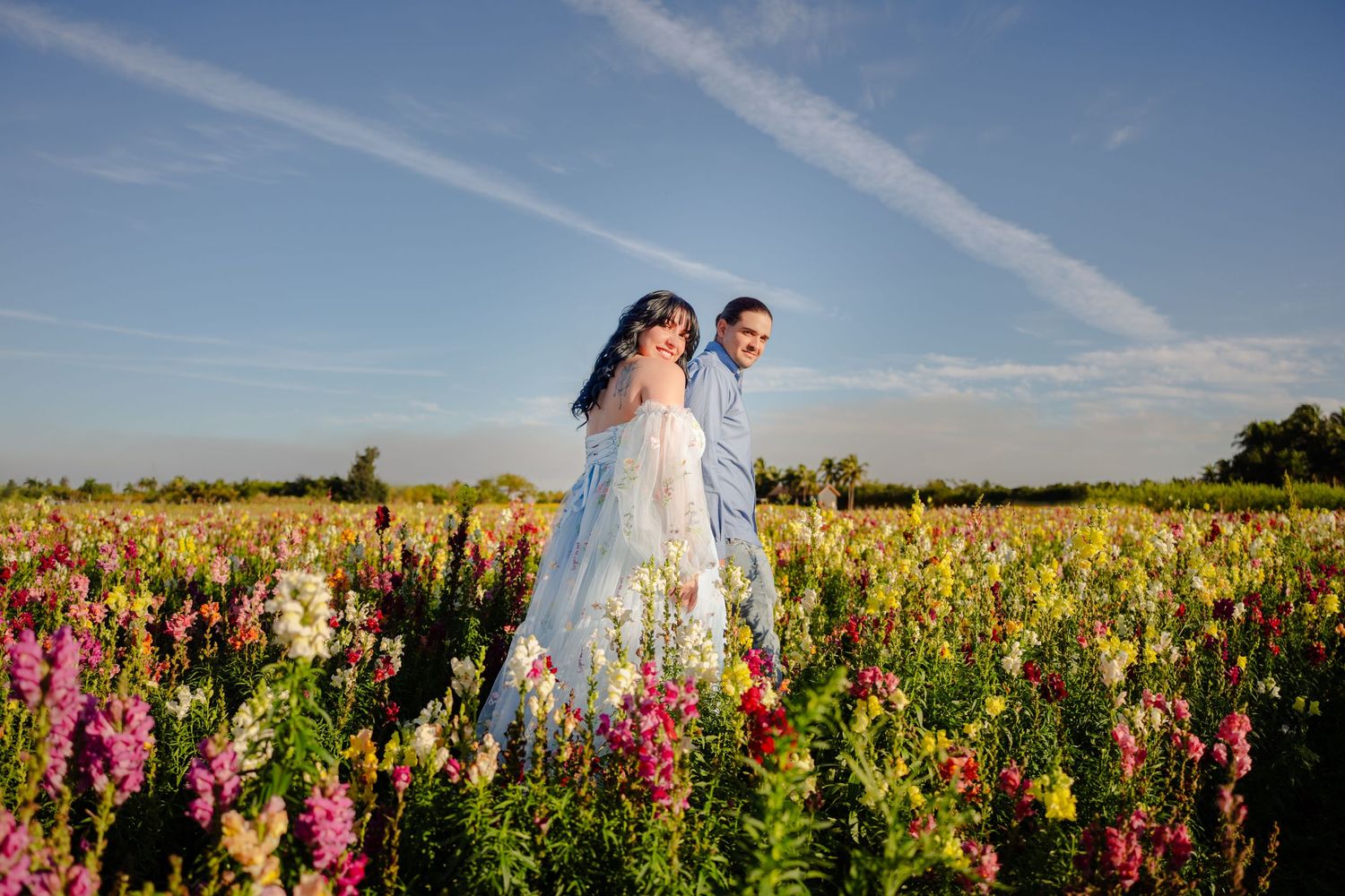 Wide shot of couple walking in field, dreamy maternity session in Miami.