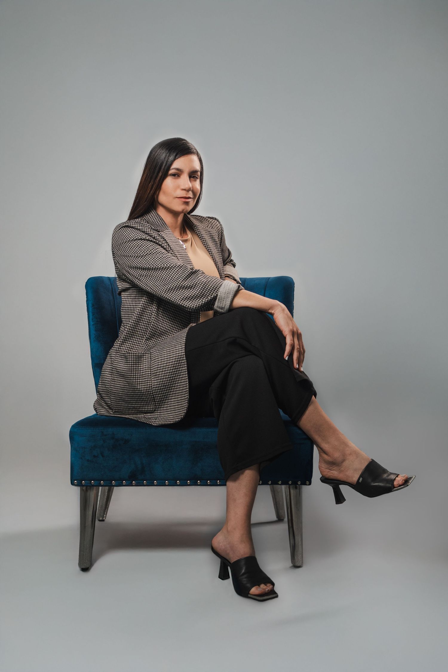 Woman seated on a blue chair in a relaxed power pose during a branding session.