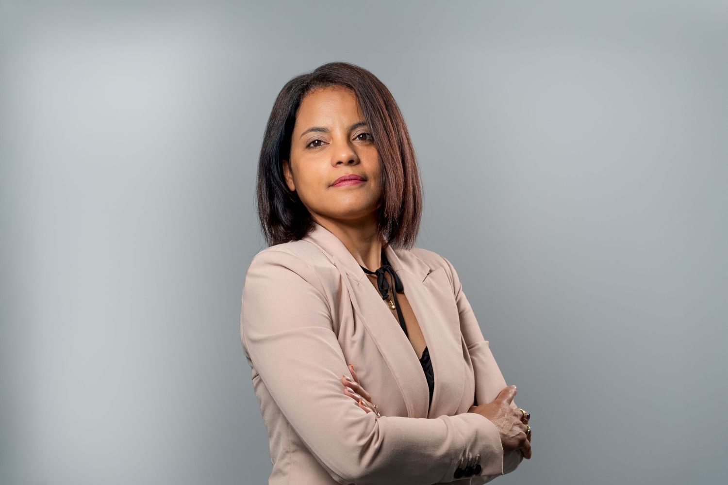 Woman in beige blazer with arms crossed during studio professional headshot
