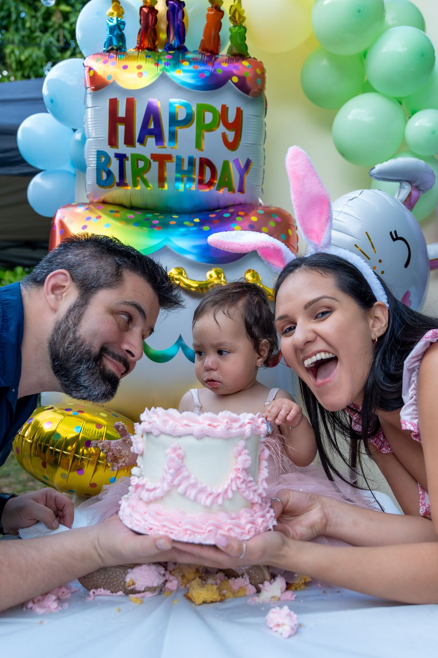 Family birthday portrait of parents smiling with their baby girl during a first birthday celebration in South Florida.