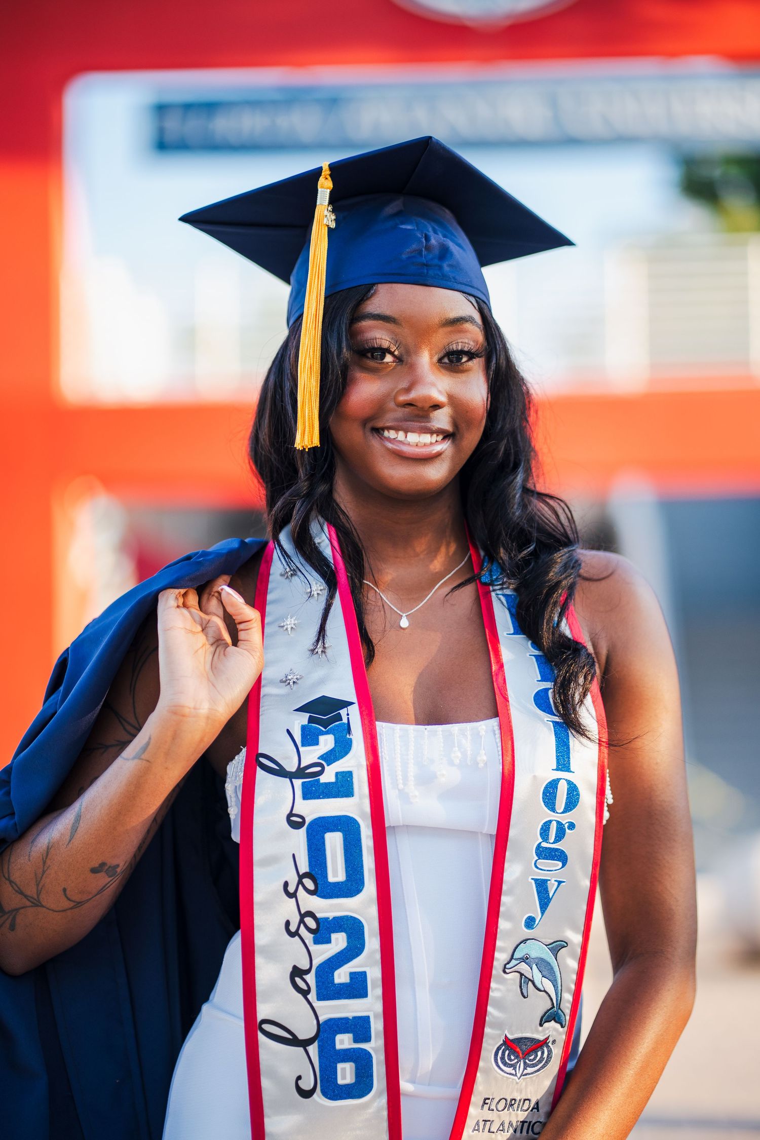 Confident FAU graduate captured in a guided portrait experience with cap and gown on Boca Raton campus