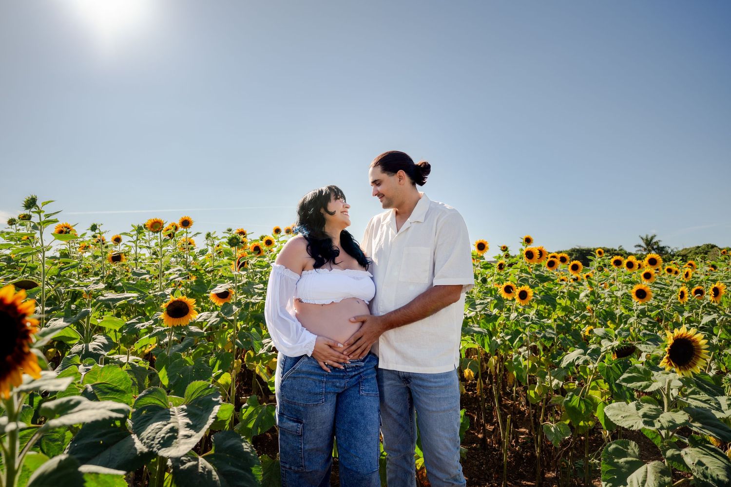 Sun-drenched maternity portrait in a sunflower field at Berry Farms, South Florida.