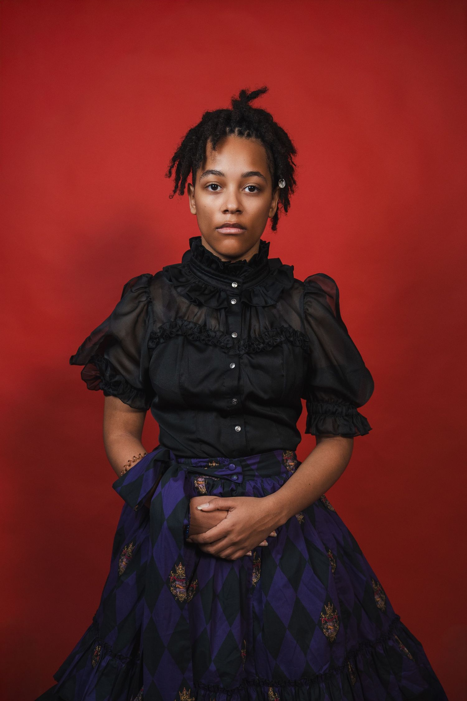 Studio senior portraits in South Florida by photographer, bold red backdrop with editorial styling and dramatic lighting