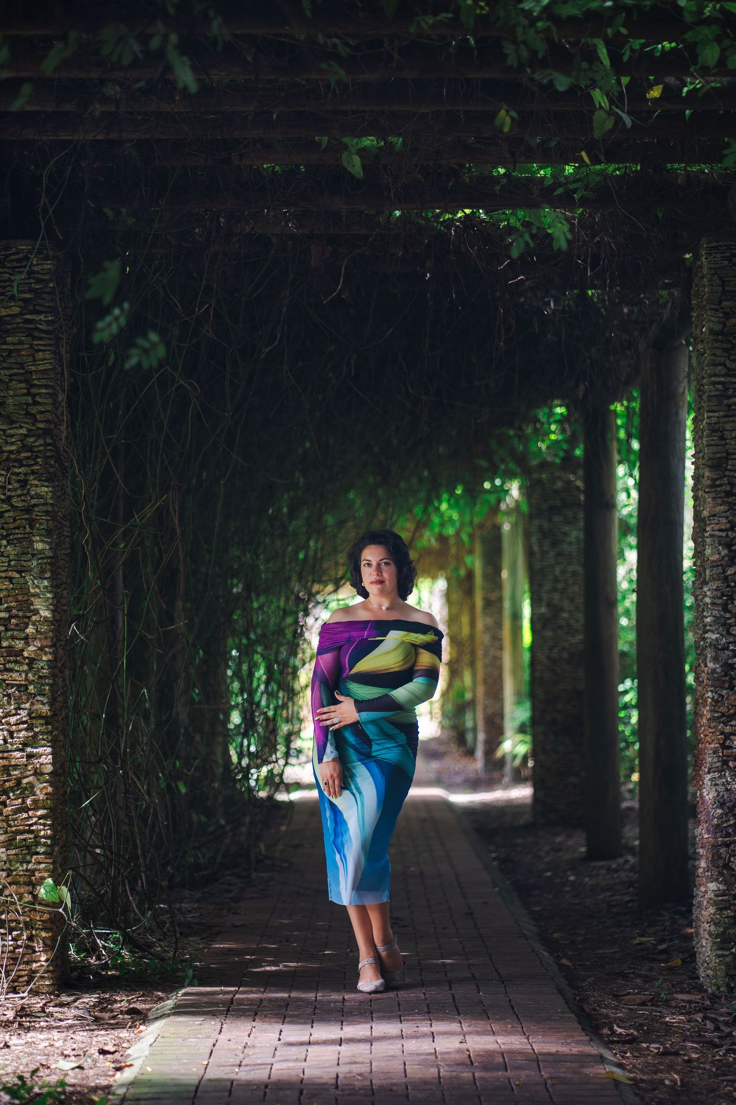 Full-body branding portrait of a woman walking through a shaded garden path at Fairchild Tropical Botanic Garden.