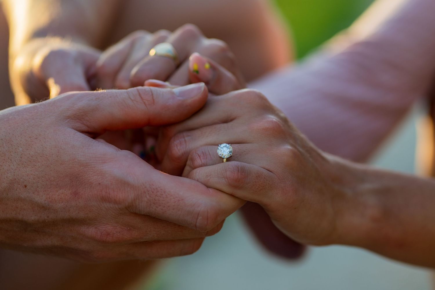 Close-up detail shot of hands during a proposal moment, highlighting connection and emotion.
