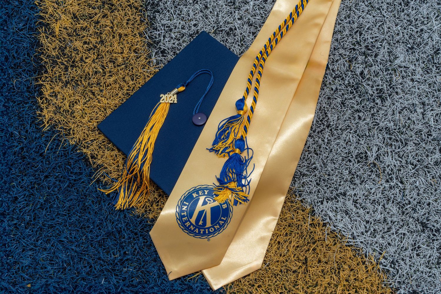 Graduation cap and gold stole on a football field, symbolizing a milestone for a Florida high school senior. South Florida graduation photog