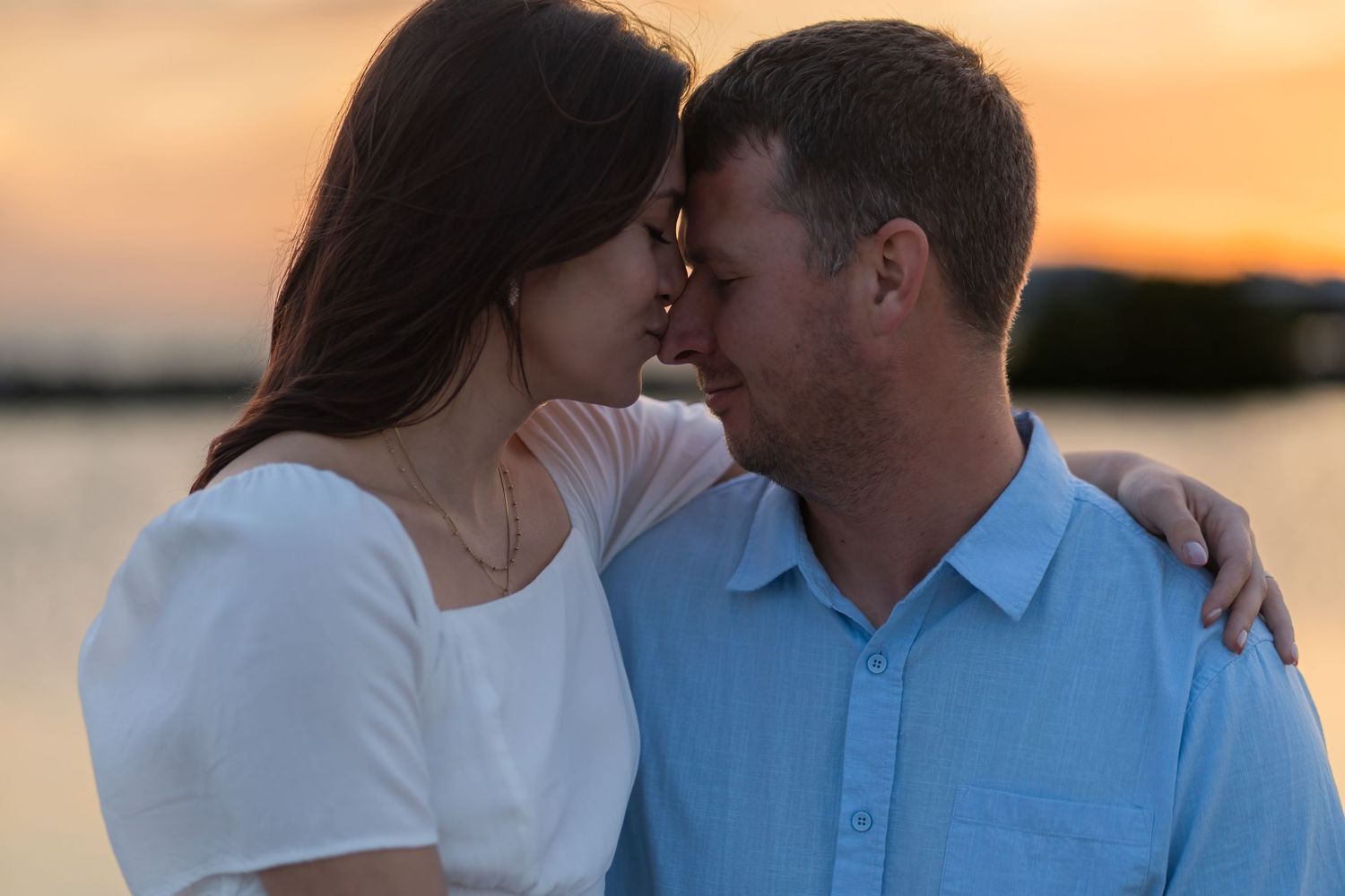 Golden hour engagement session in Hollywood, FL with a couple embracing by the water.