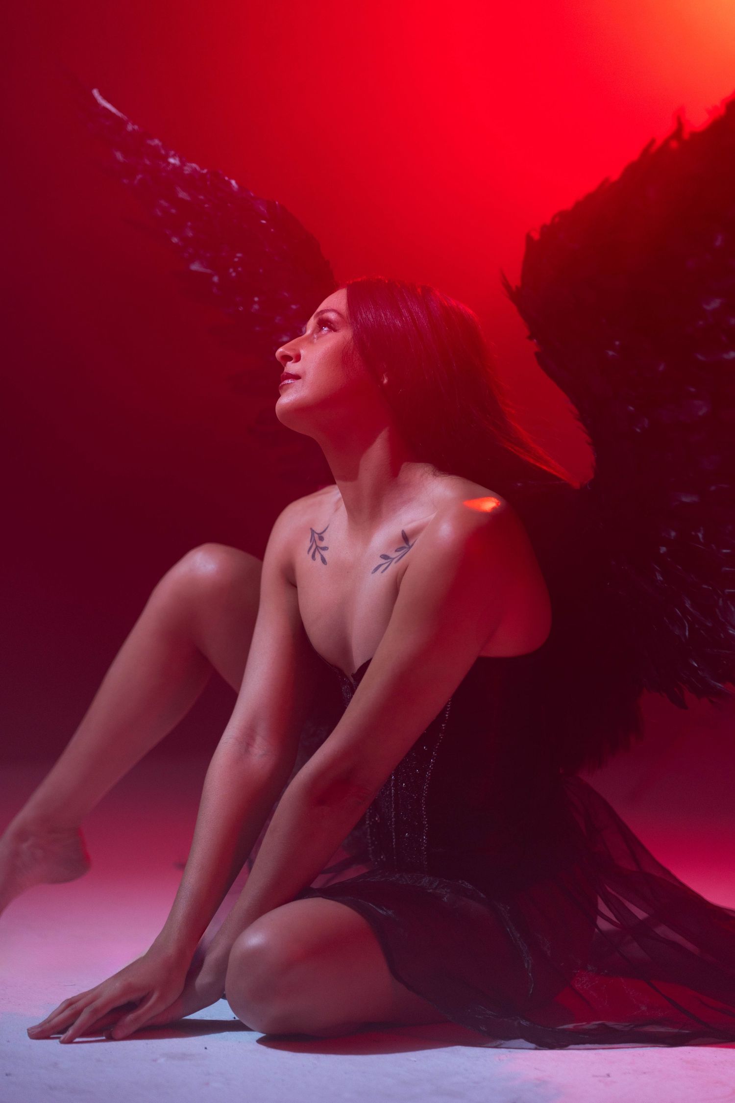 Dark angel fantasy portrait at CFX Studio, Miami, FL – woman with black wings in a moody red-lit setting.