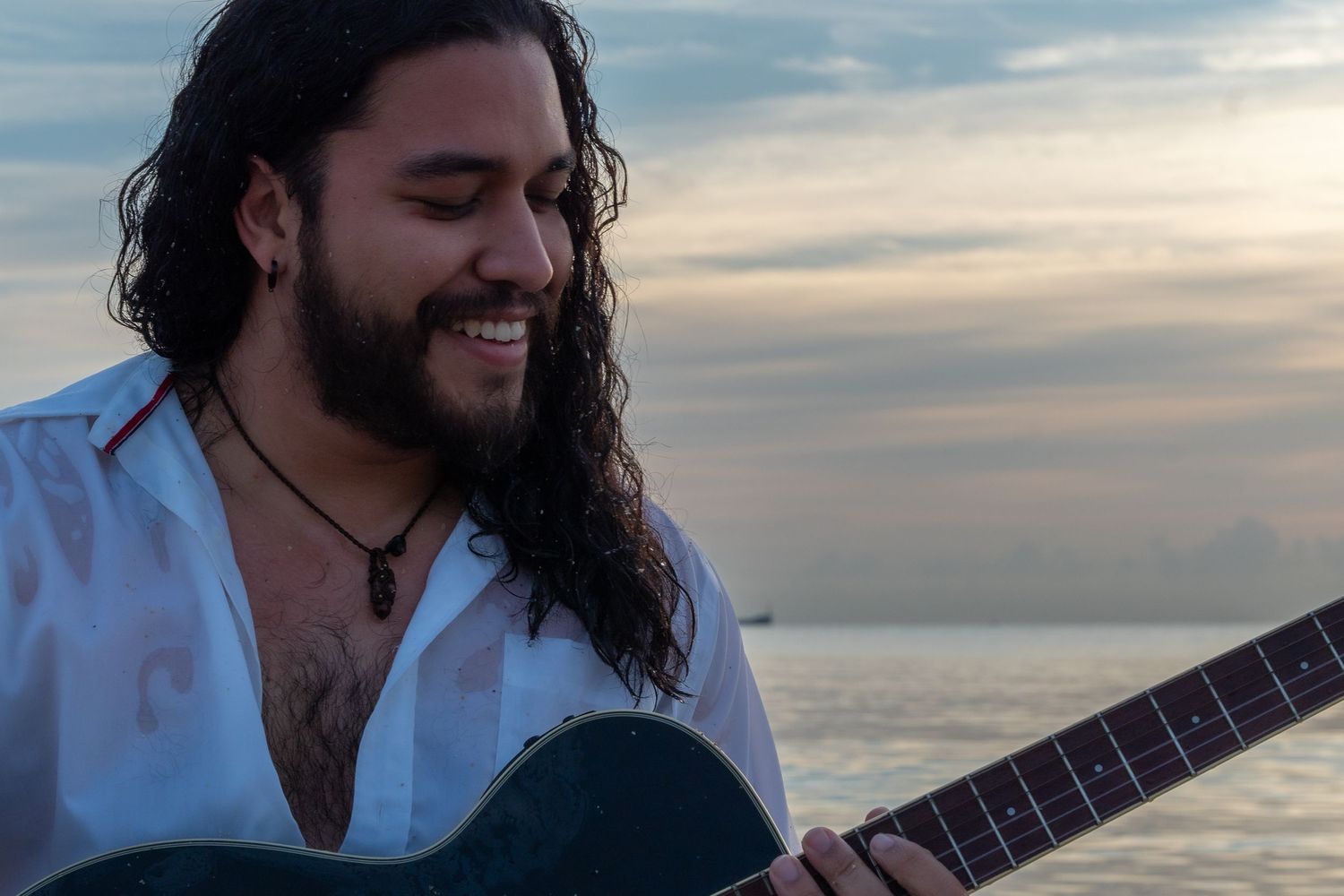 Musician on the shore – guitarist plays his instrument against the backdrop of a Miami sunset.
