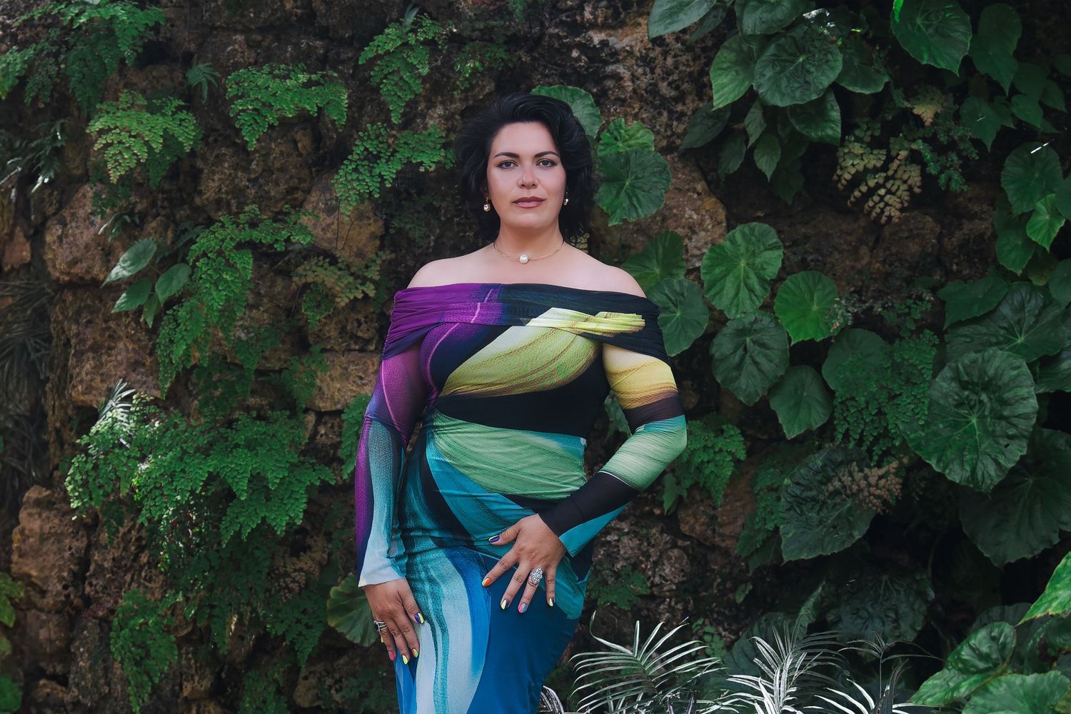 Editorial branding portrait of a woman standing confidently against a wall of tropical plants at Fairchild Garden.