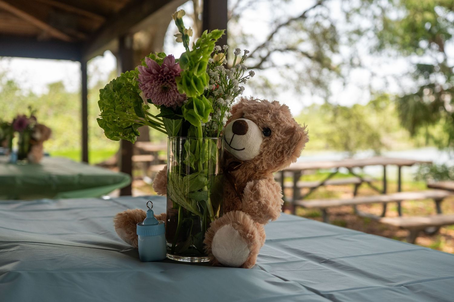 Decorative table settings with natural elements and candles arranged in a rustic outdoor baby shower at cb smith park