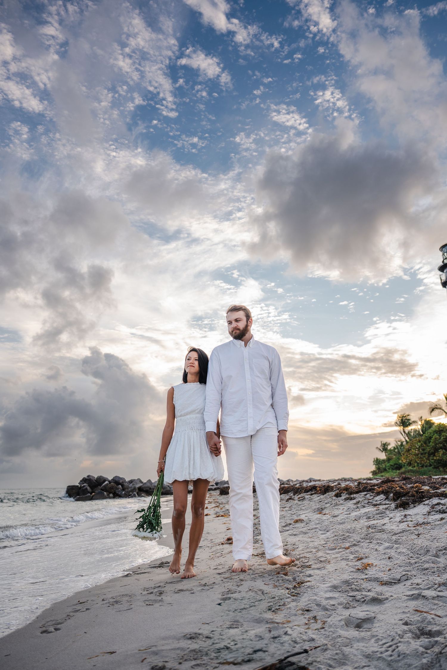 Engaged couple standing together on the beach with dramatic clouds at Bill Baggs Cape Florida.