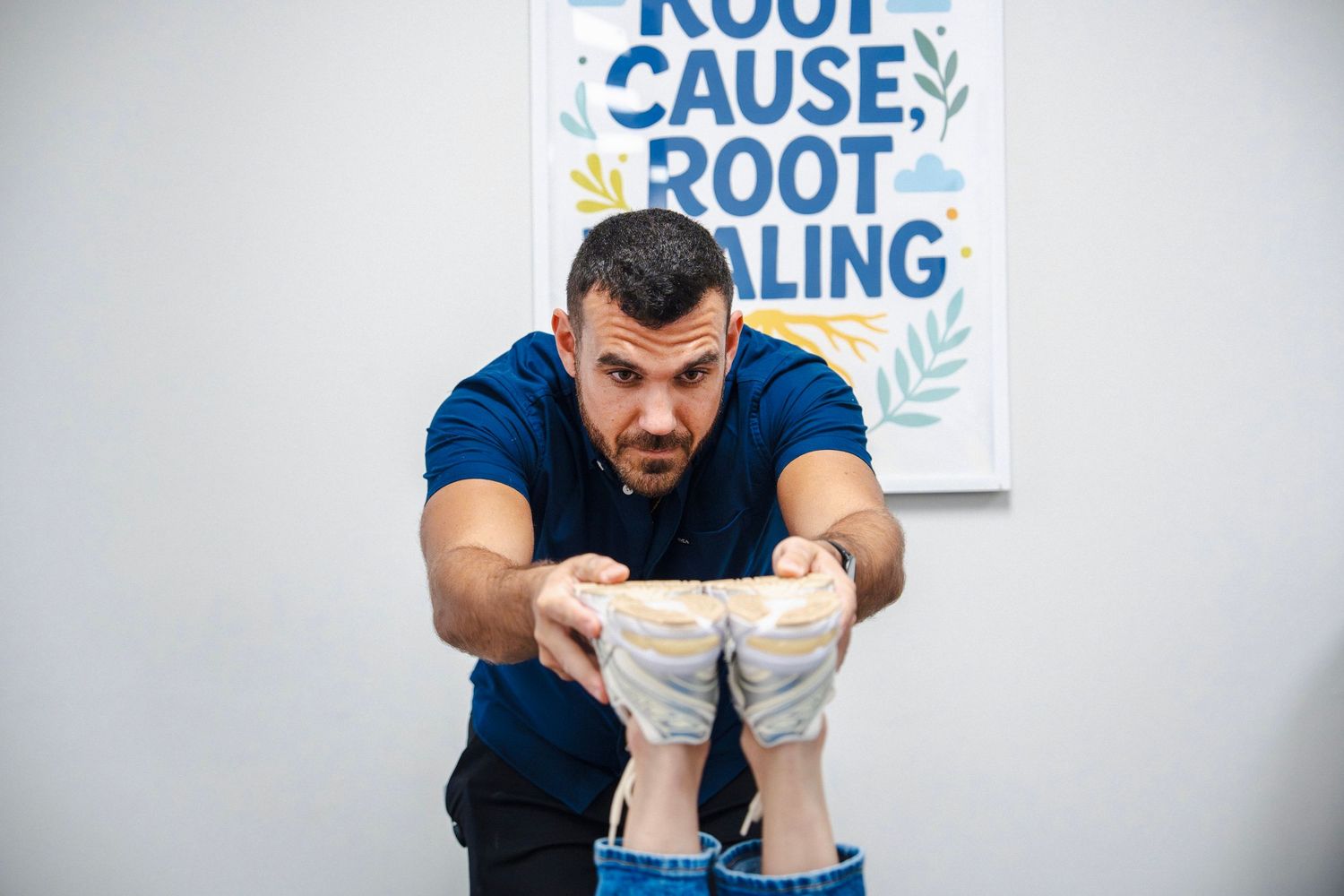 A person in a navy shirt performs stretching exercises in front of a blue and white motivational wall sign.