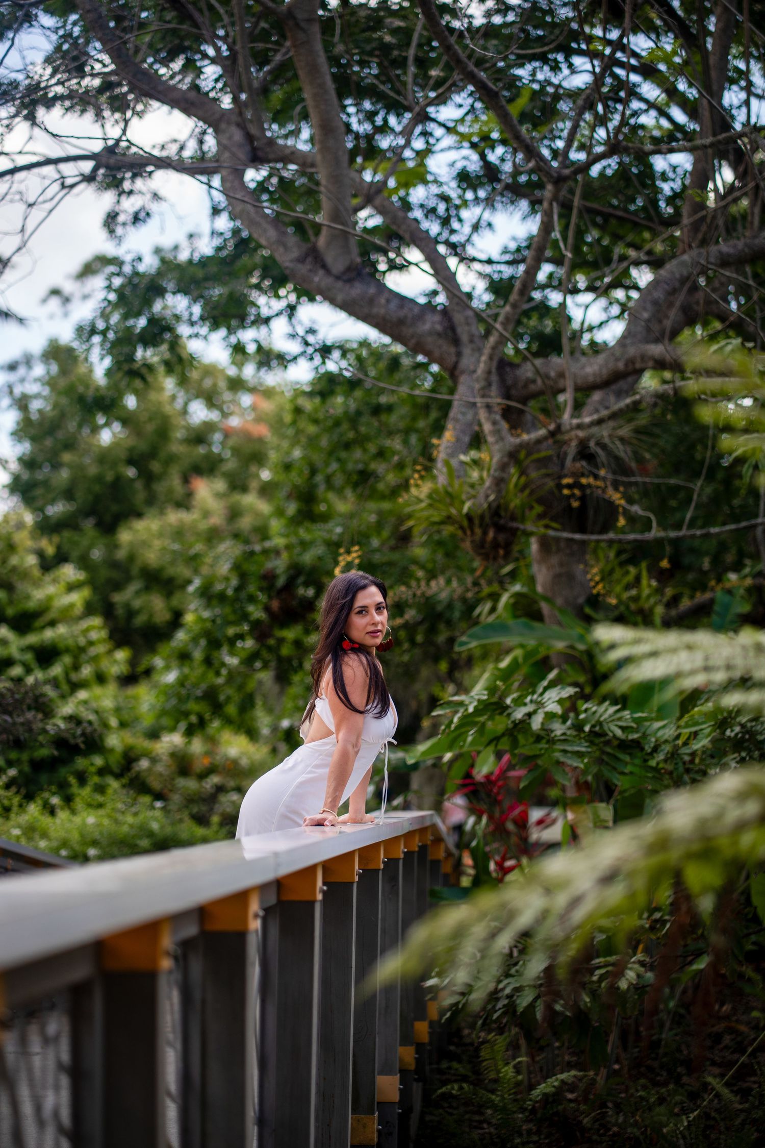 South Florida portrait of woman leaning on wooden railing surrounded by greenery
