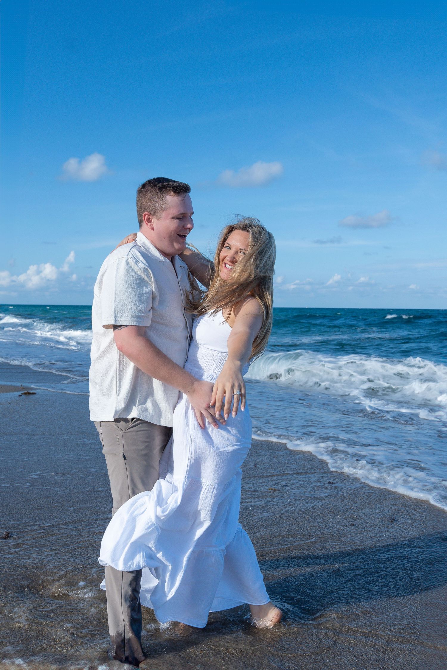 Couple walking along the shoreline during a beach engagement session in South Florida at golden hour.