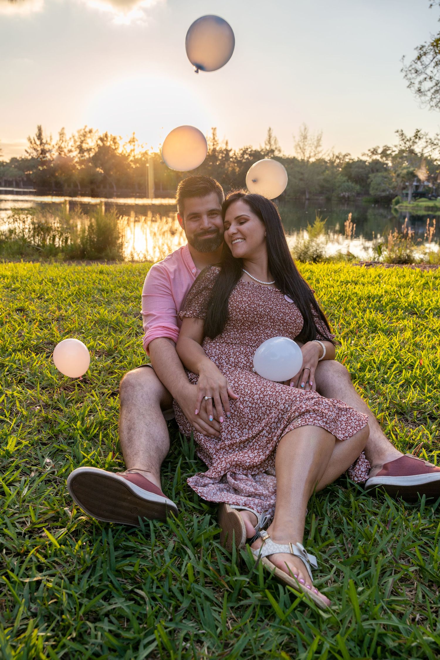 Casual maternity photo of an expecting couple seated on the grass during a relaxed South Florida session.