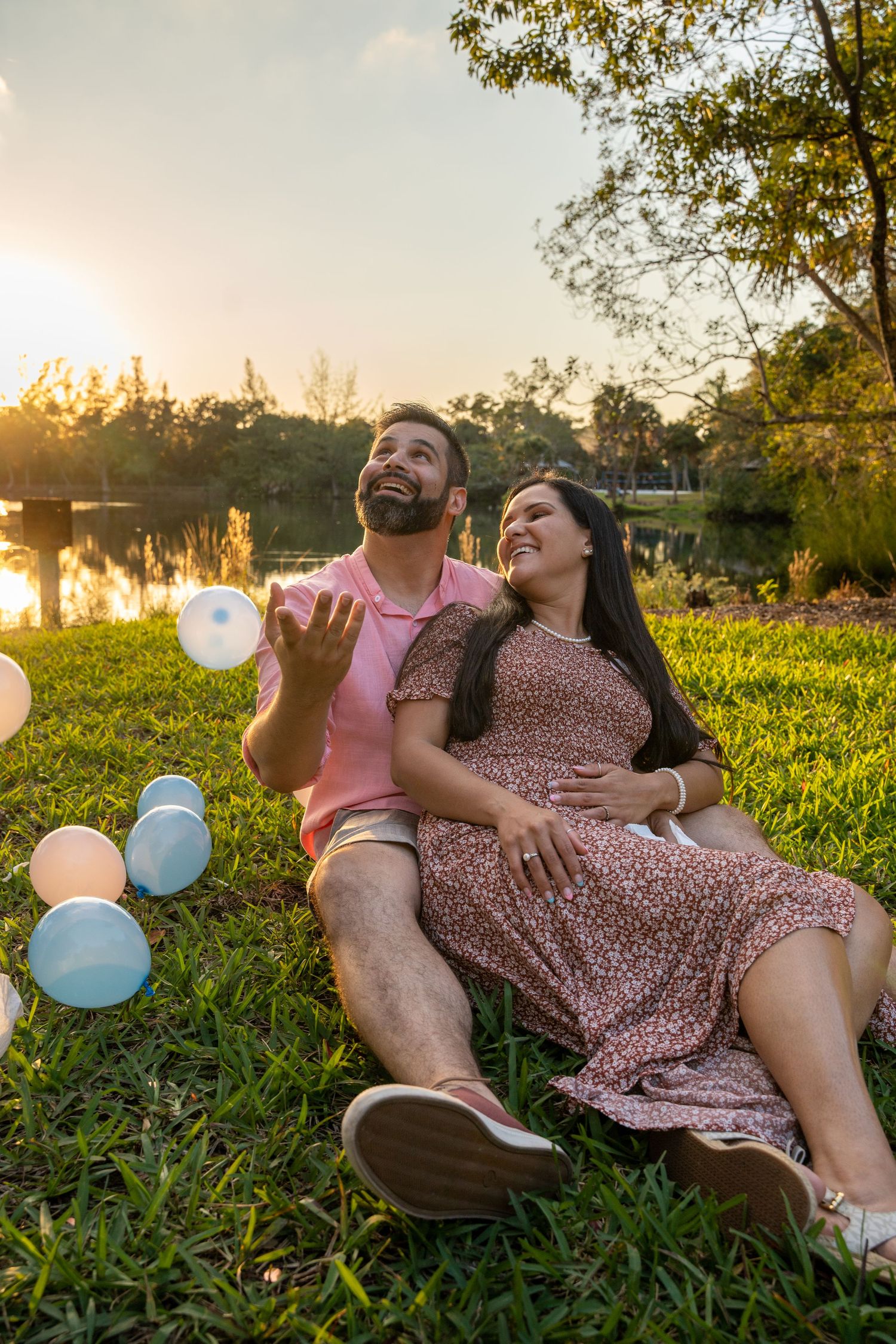 Expecting couple relaxing on the grass at sunset during an outdoor maternity session in South Florida.