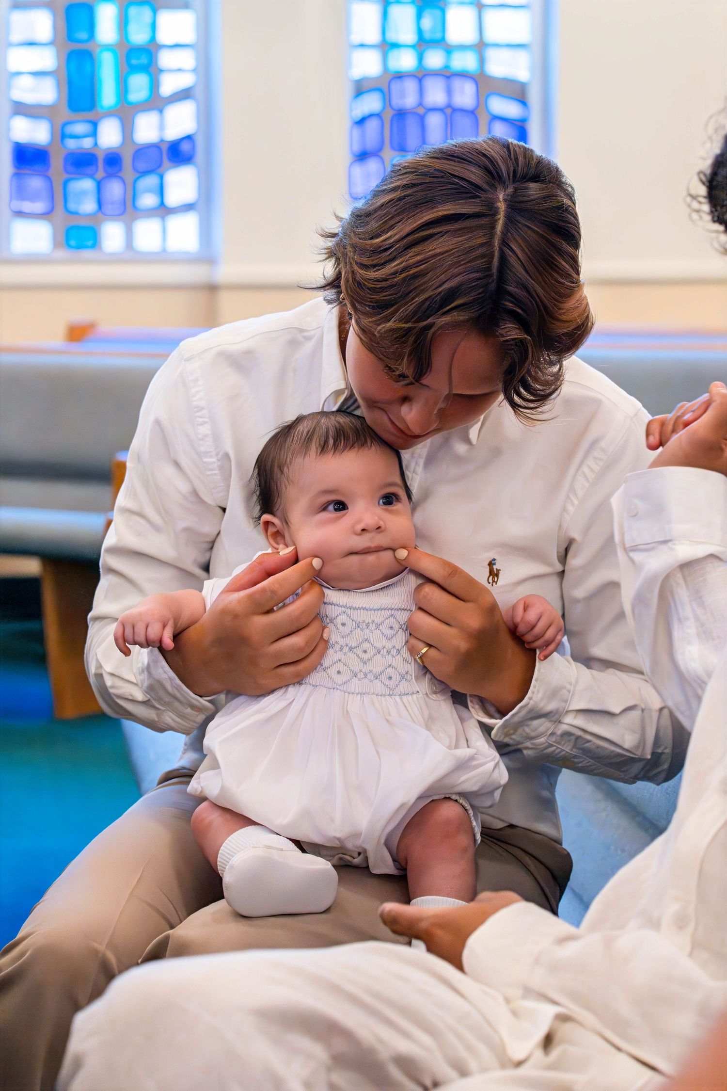 Close-up of a parent holding their baby inside a church following the baptism ceremony.