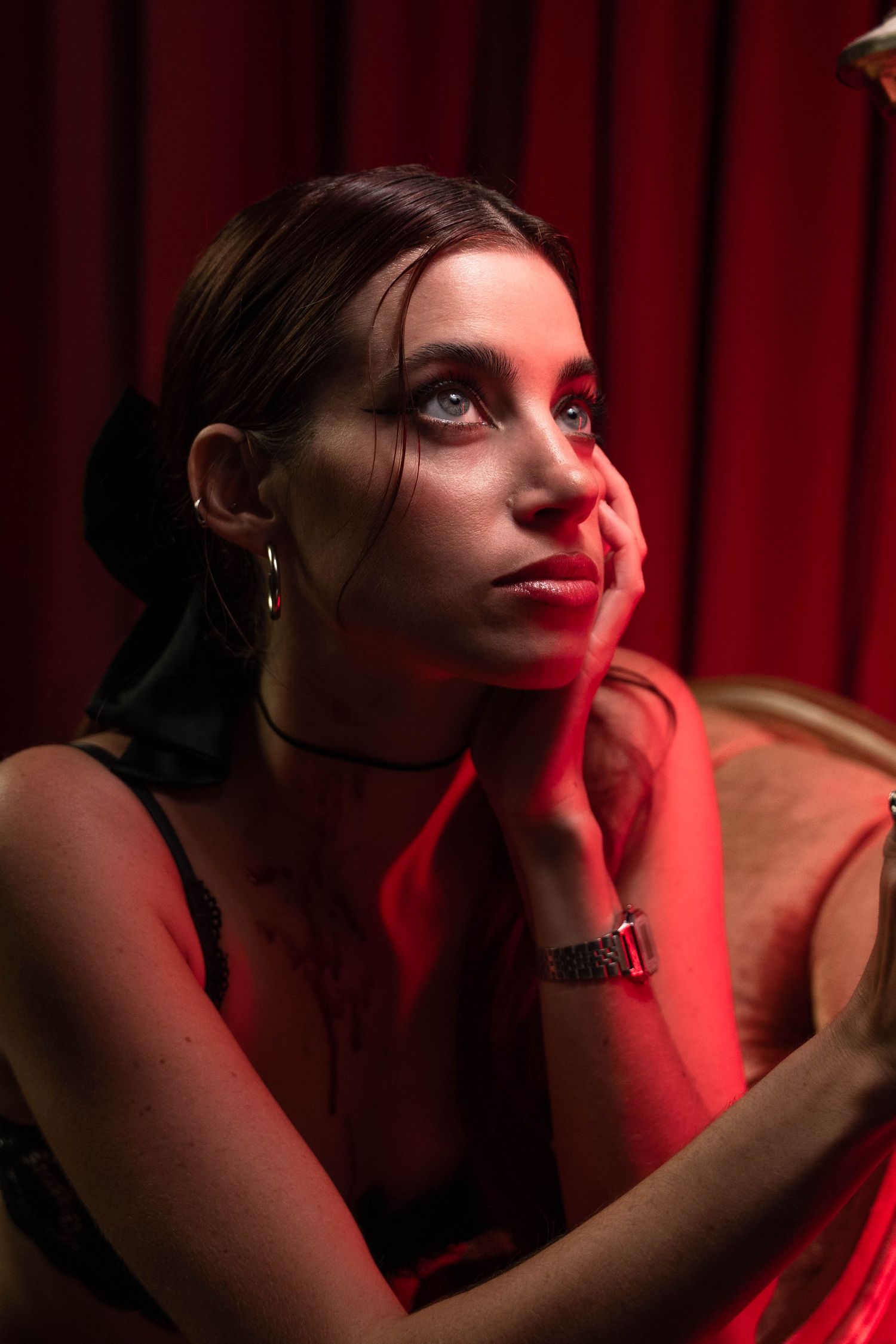 Theatrical mood portrait in West Palm Beach, FL – woman under deep red lighting with a pensive expression.
