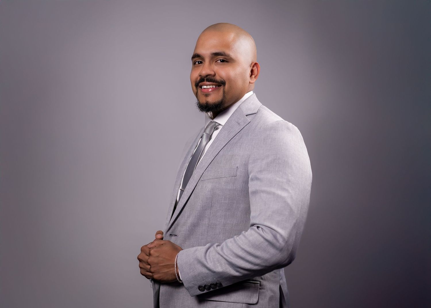 Man in light gray suit smiling during professional studio headshot session