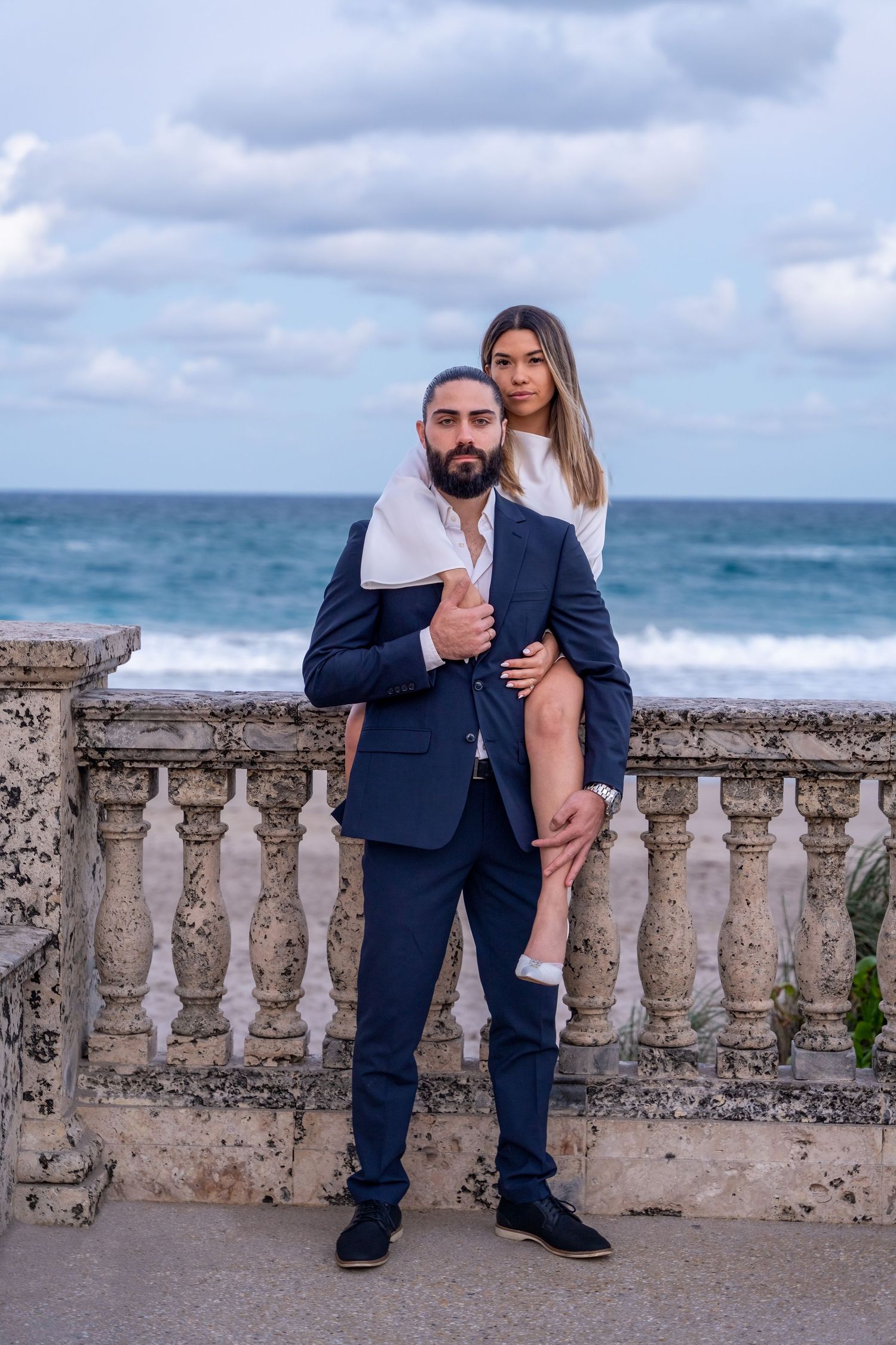 Romantic engagement portrait on Worth Avenue in Palm Beach, FL, with classic stone railing and ocean view.