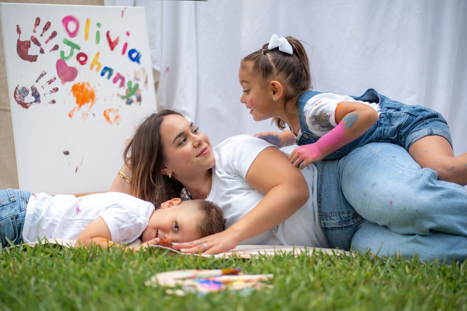 Cozy moment between mom and daughters during an outdoor family painting session in South Florida.