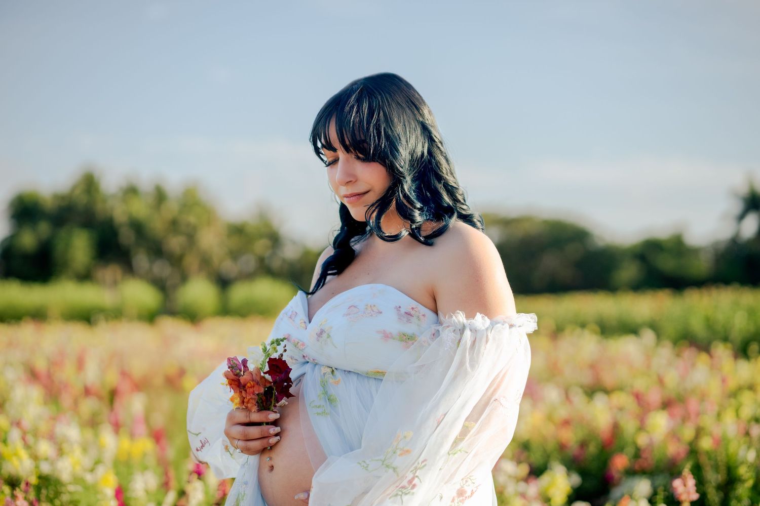 Golden light maternity photo in wildflower field, natural and elegant in South Florida.