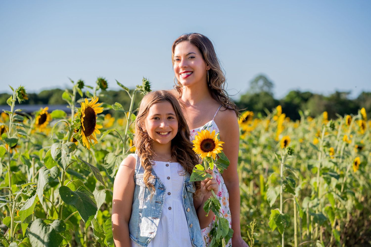 Mother and daughter holding sunflowers in a sunflower field near Fort Lauderdale.