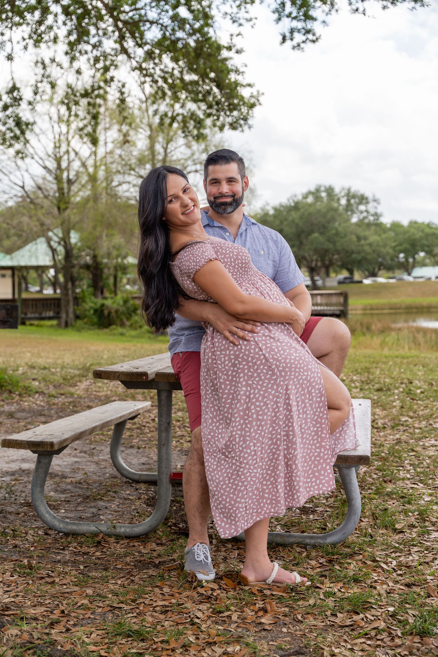 Expecting couple seated together at a park during a relaxed South Florida maternity photo session.