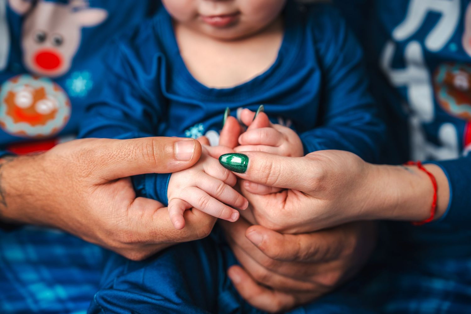 Close-up holiday detail of a baby’s hands holding a Christmas ornament during a festive family session.