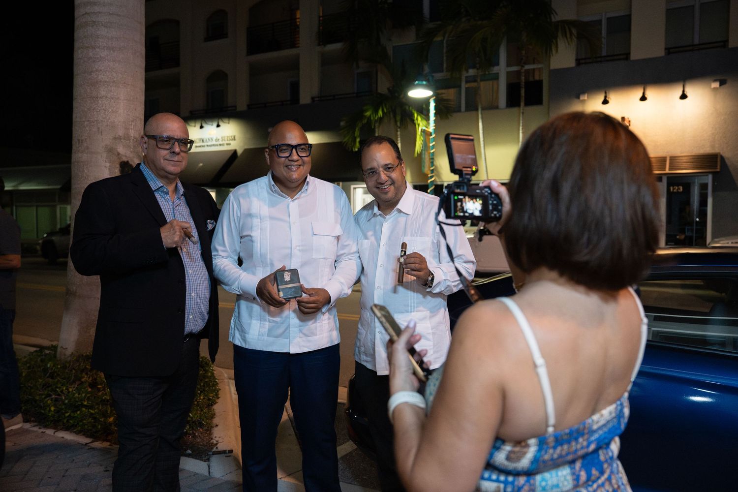 Guests gathered outside Bartolo’s Wine Bar & Cigar Shop during the grand opening event, photographed candidly at night.