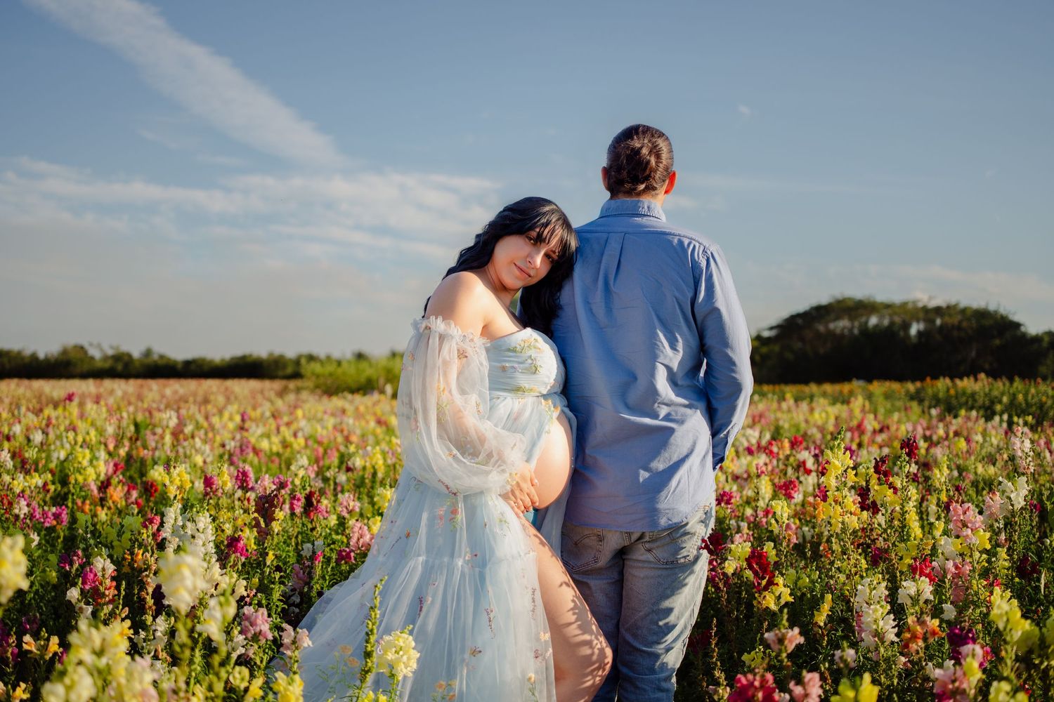 Couples maternity portrait walking through colorful wildflowers in Miami.