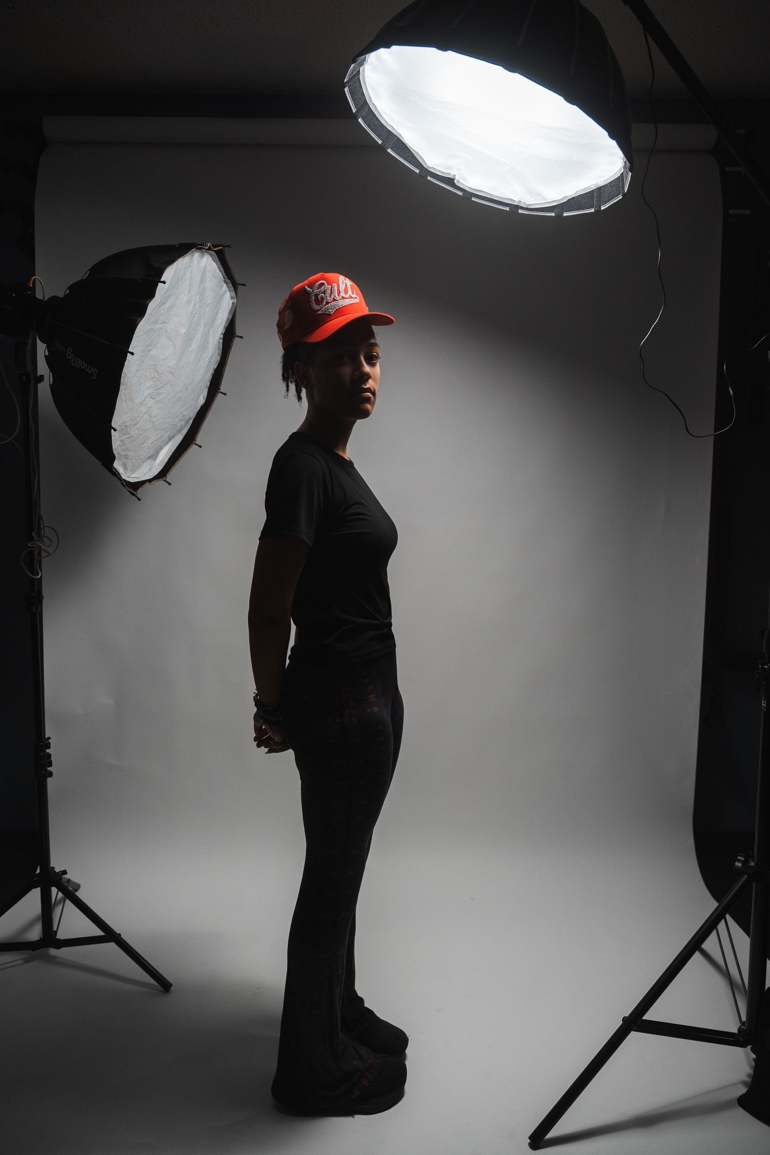 Behind-the-scenes style senior portrait showing studio lighting equipment and a strong profile pose.