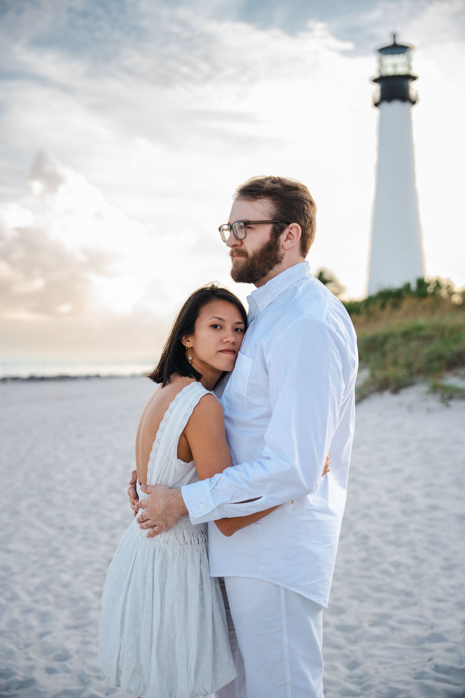 Close, intimate engagement portrait of a couple embracing at Bill Baggs Cape Florida with soft evening light.