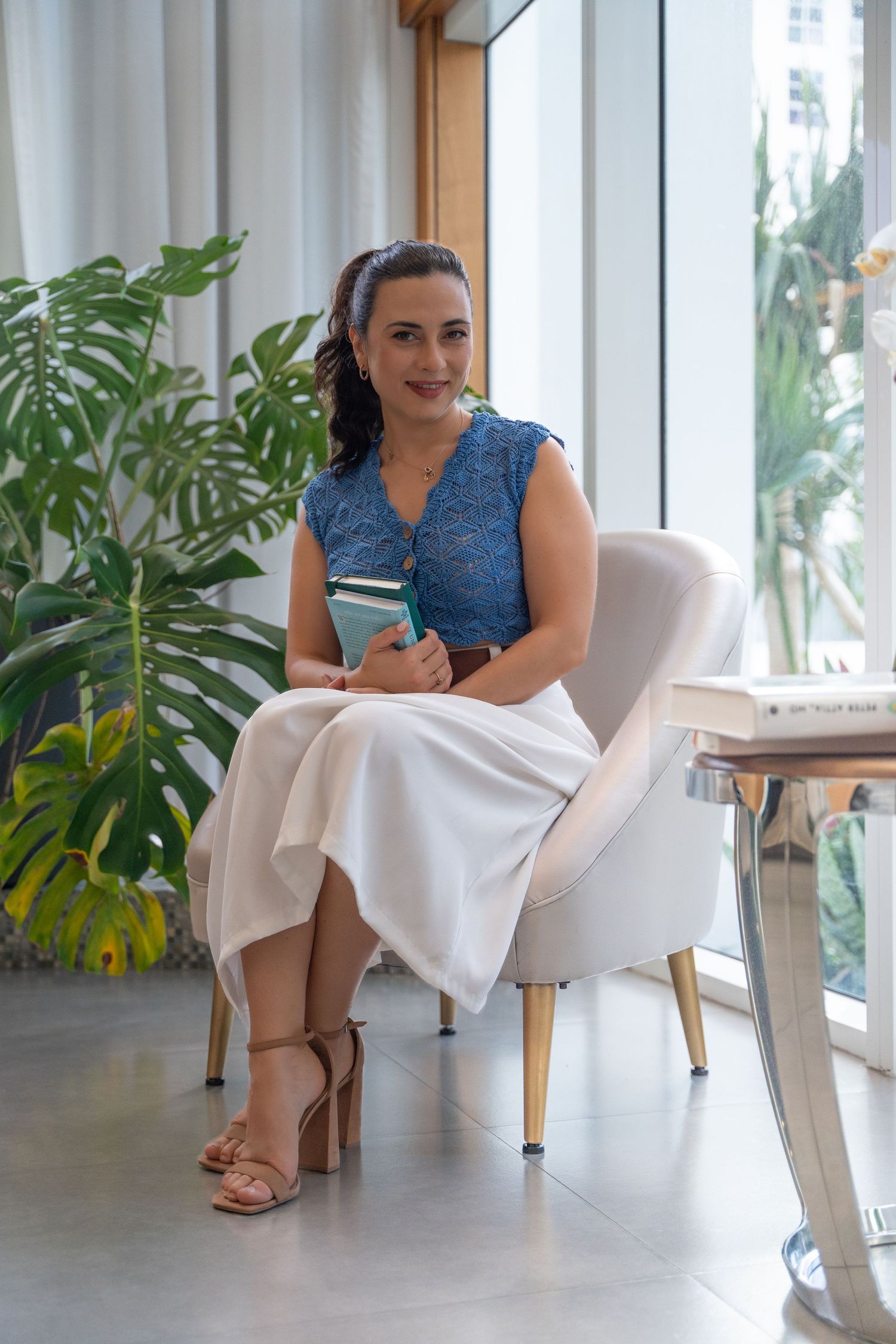Elegant personal branding session in Miami, FL – confident woman sitting in a modern, plant-filled workspace.