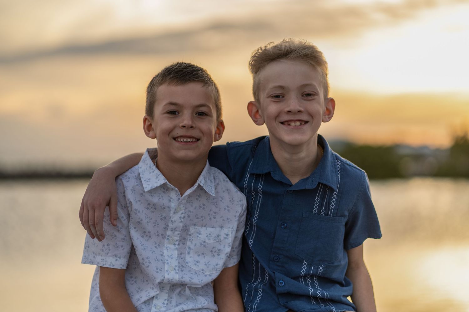 Sibling portrait in Miami, FL – two brothers smiling at sunset by the water during a relaxed and joyful family session.