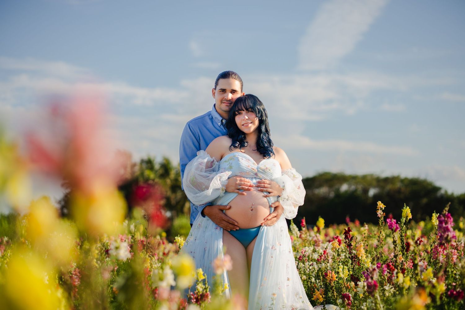 Golden hour maternity session with couple standing in flower field, South Florida.