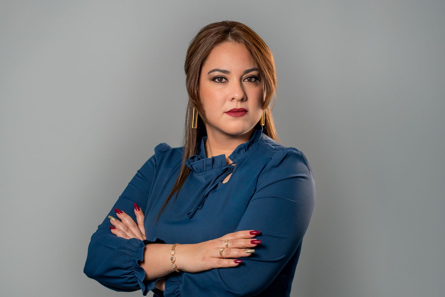 Woman with arms crossed in blue blouse during studio headshot session