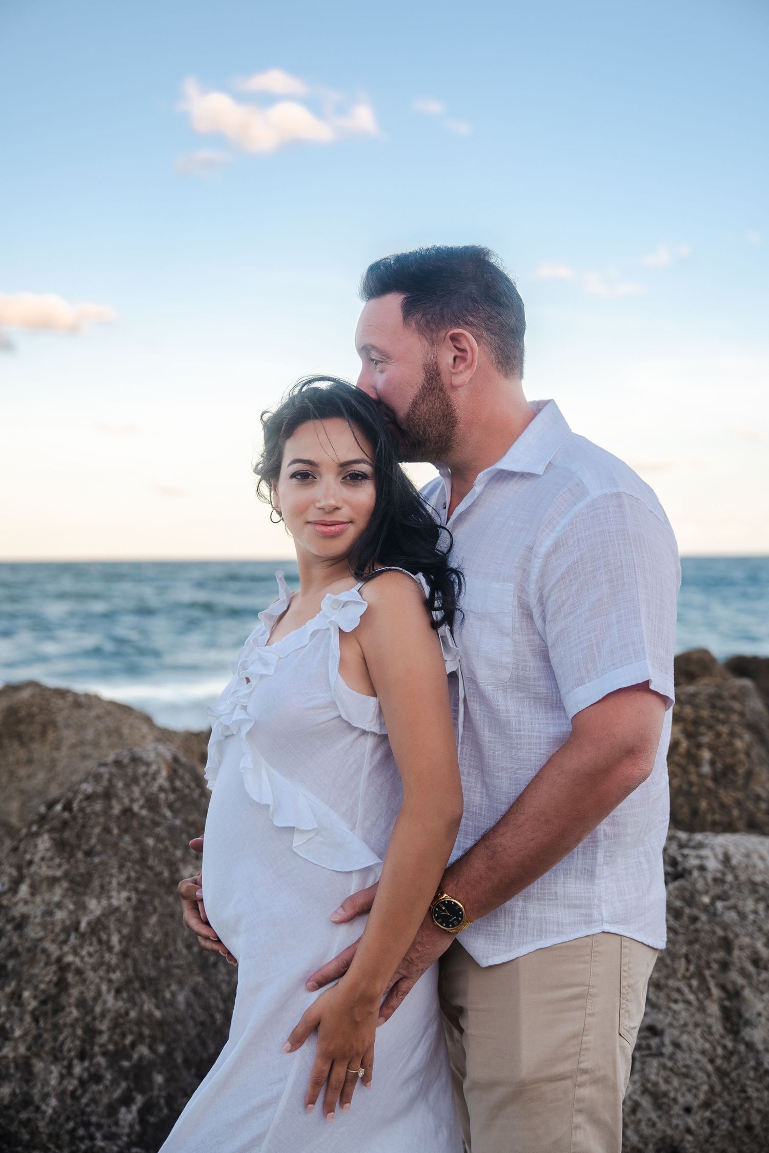 Expecting couple standing together near the ocean during a maternity announcement session.