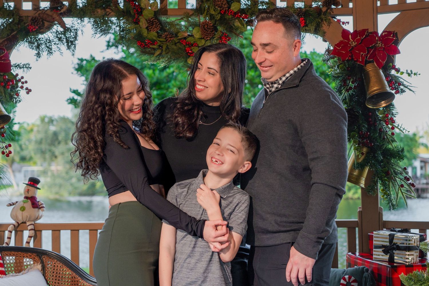 Family smiling together during a holiday mini session with festive greenery and seasonal décor in South Florida.