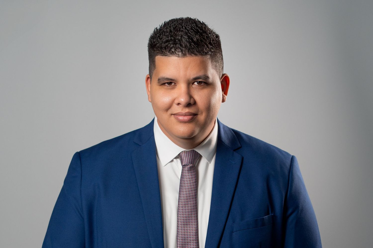 Man in blue suit posing for professional studio headshot