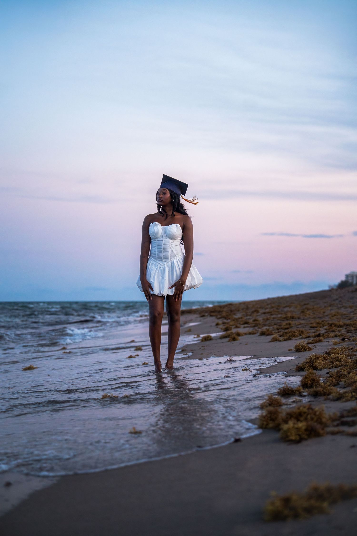 Beach graduation portrait in South Florida capturing FAU graduate in a guided, natural sunset session