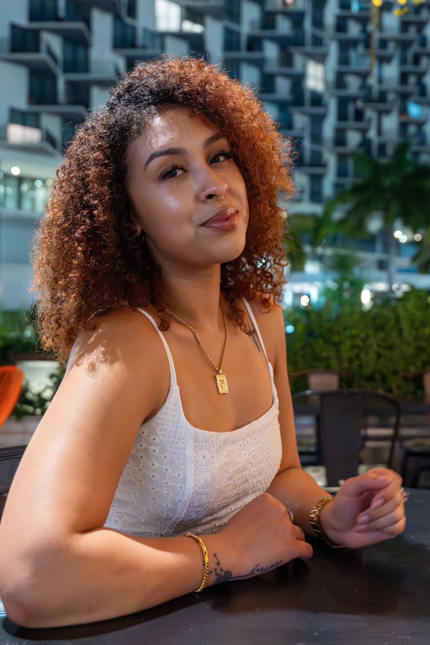 Urban portrait session in Miami – stylish woman enjoys a relaxed moment at a rooftop bar with a city skyline backdrop.