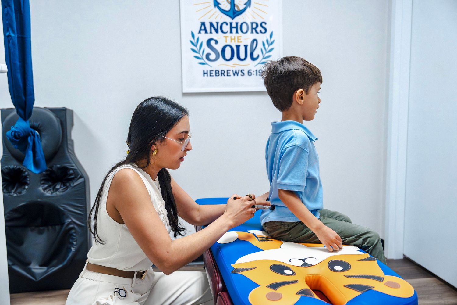 Chiropractor examining young child’s posture in treatment room during lifestyle branding session