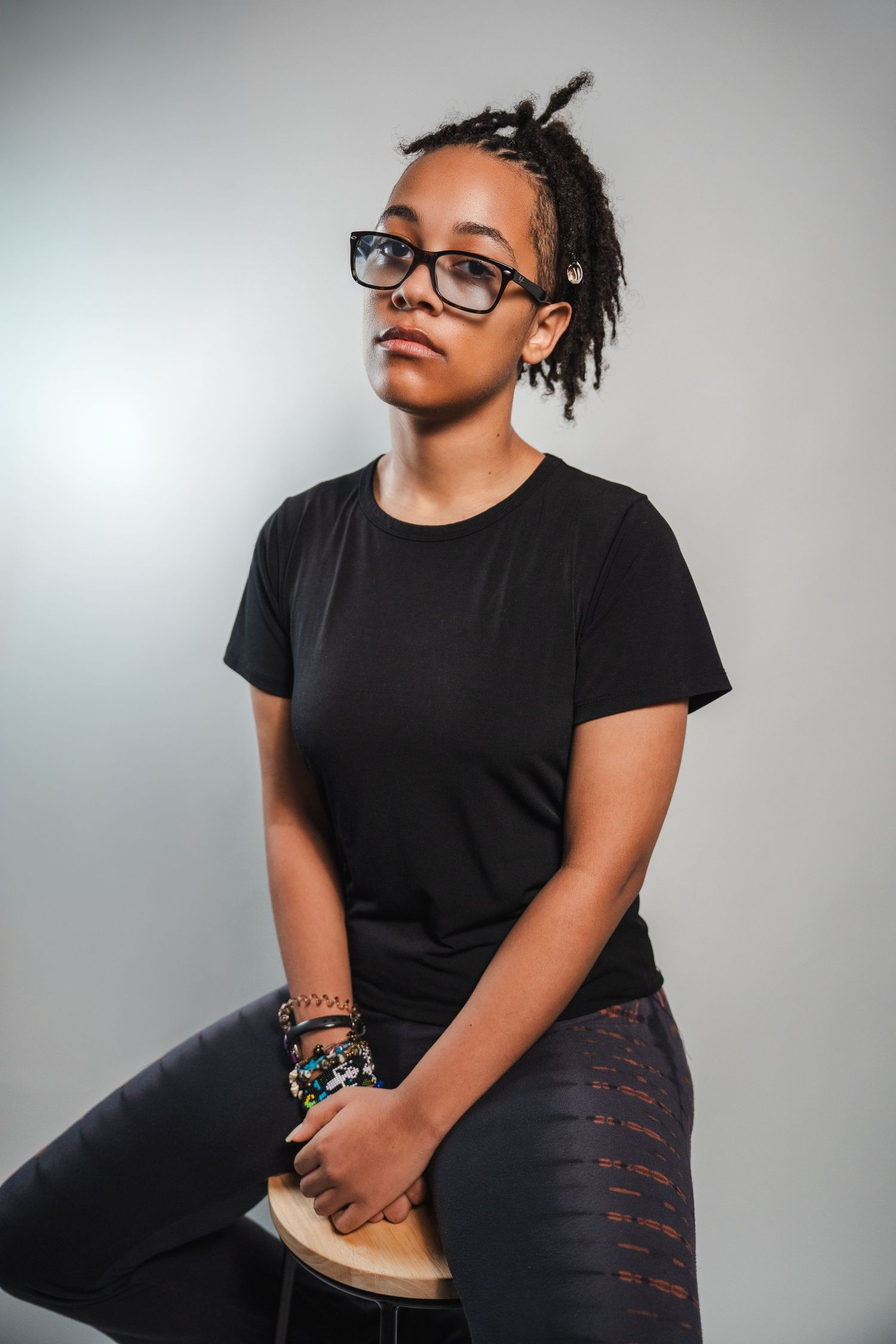 Studio senior portrait of a graduate seated casually, photographed with clean lighting and a modern, editorial feel.