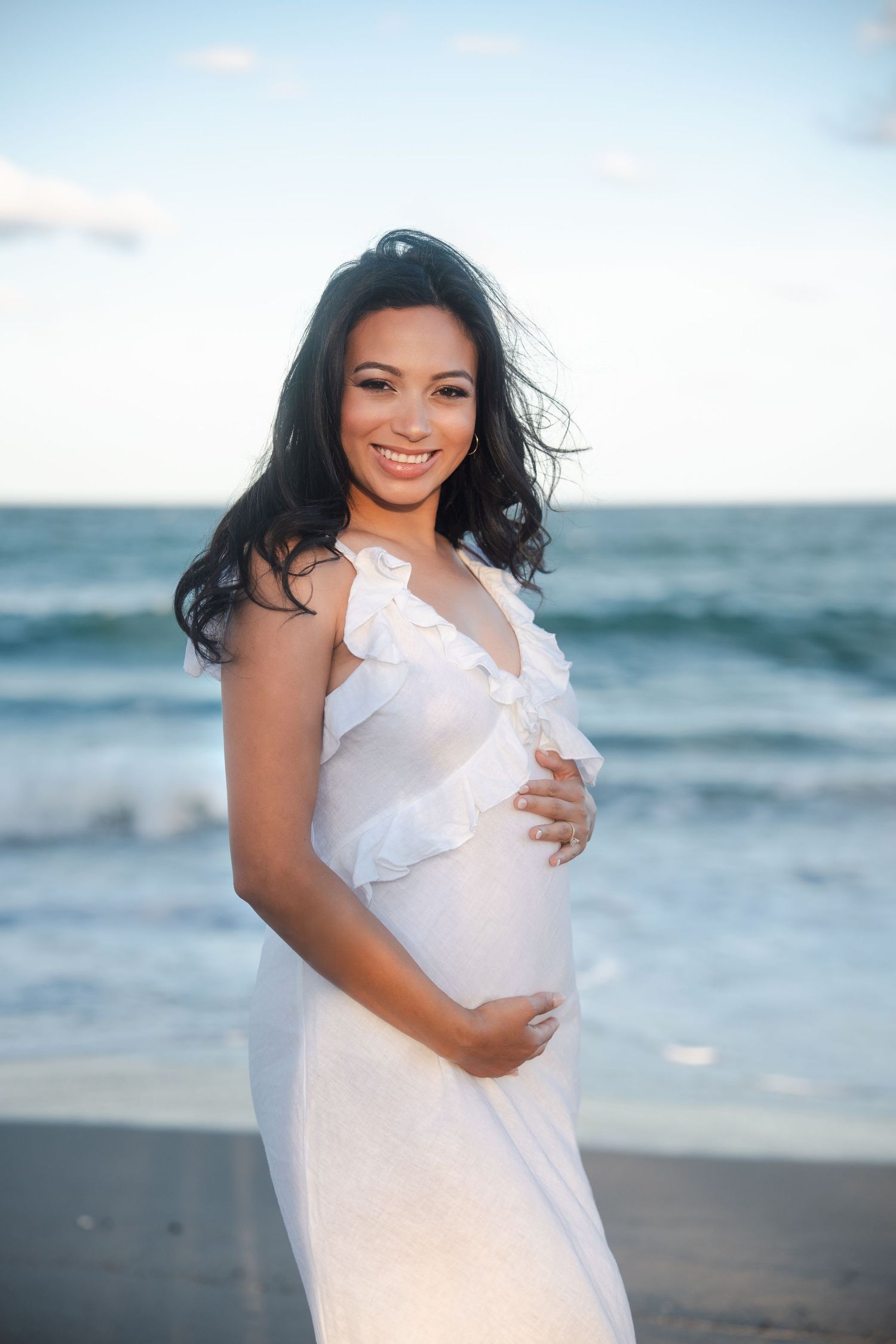 Maternity pregnancy announcement portrait of an expecting mother standing by the ocean in Deerfield Beach, Florida.