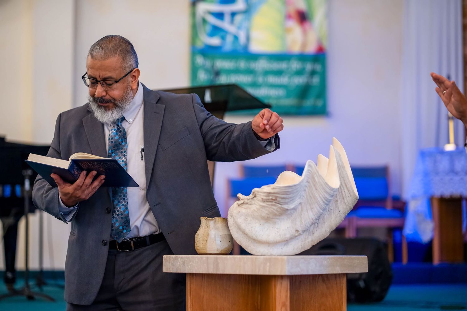 Priest reading scripture during a baptism ceremony inside a church, documenting a sacred moment in a family baptism service.