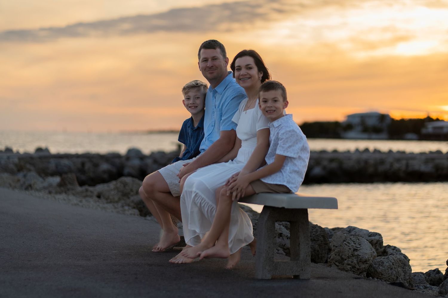Family photo session at sunset in Harry Harris Park, FL with parents and kids by the water.