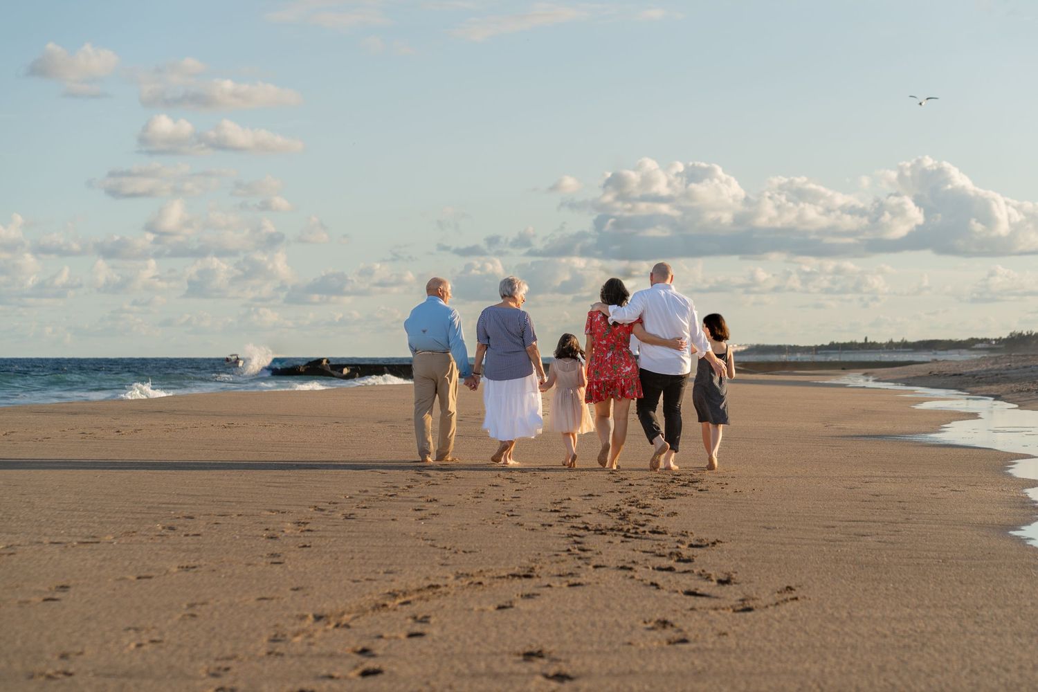 Multi-generational family walking along the shore in West Palm Beach, FL – footprints in the sand at golden hour.
